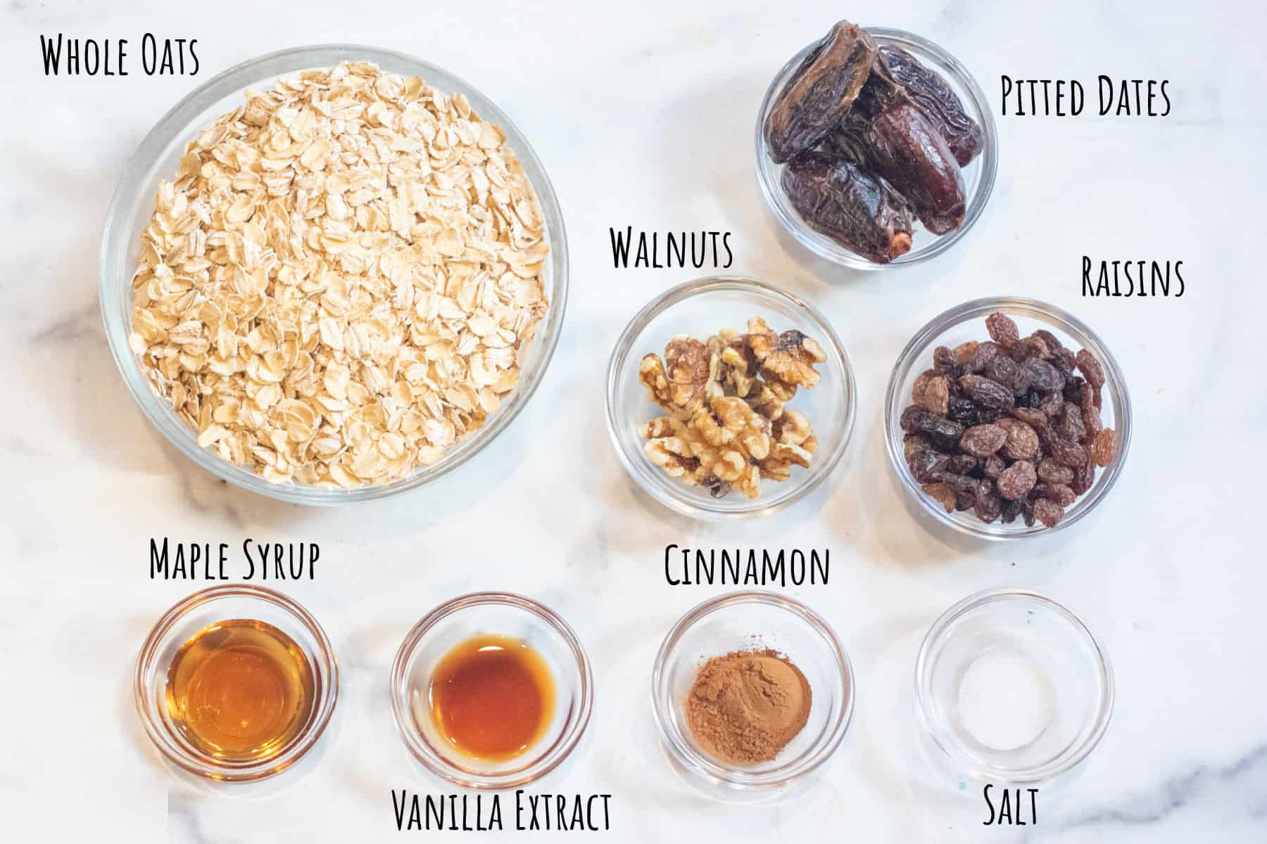 a bowl of oats, dates, raisins, maple syrup, vanilla extract, cinnamon, salt, and walnuts all labeled.
