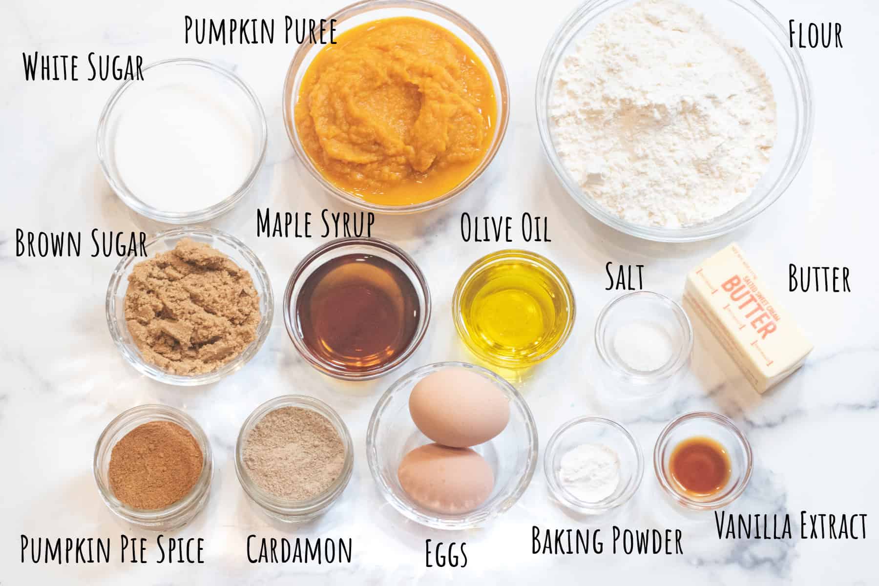 bowls of pumpkin puree, flour, sugars, maple syrup, oil, butter, eggs, spices, vanilla extract all labeled.