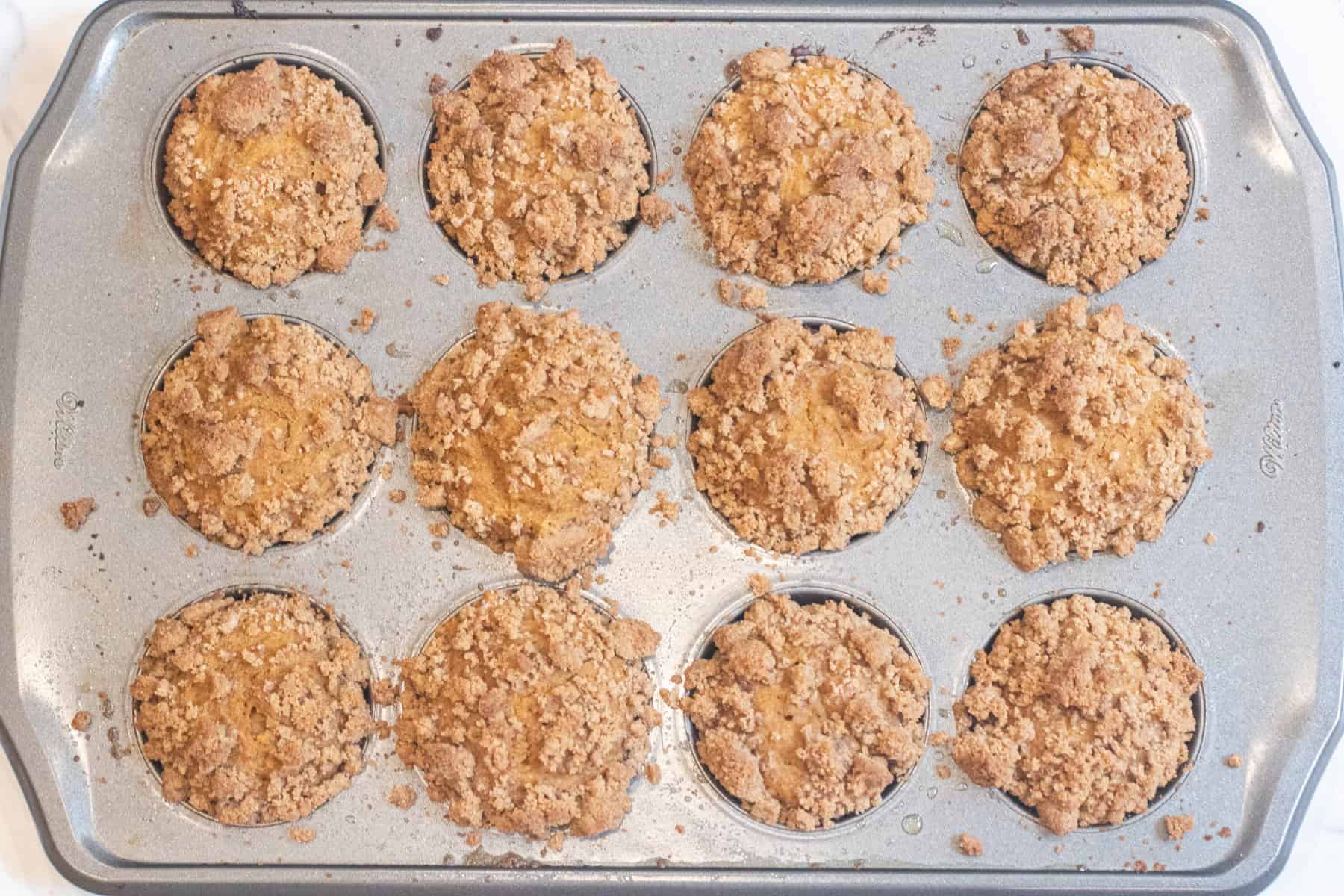 a tray of baked muffins with a crumble on top.