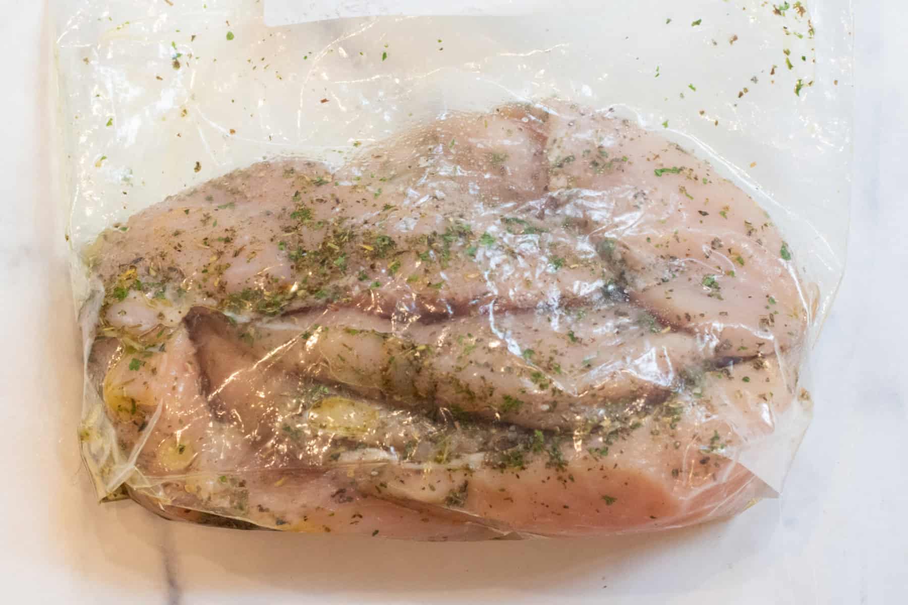 a bag of raw seasoned chicken marinating.