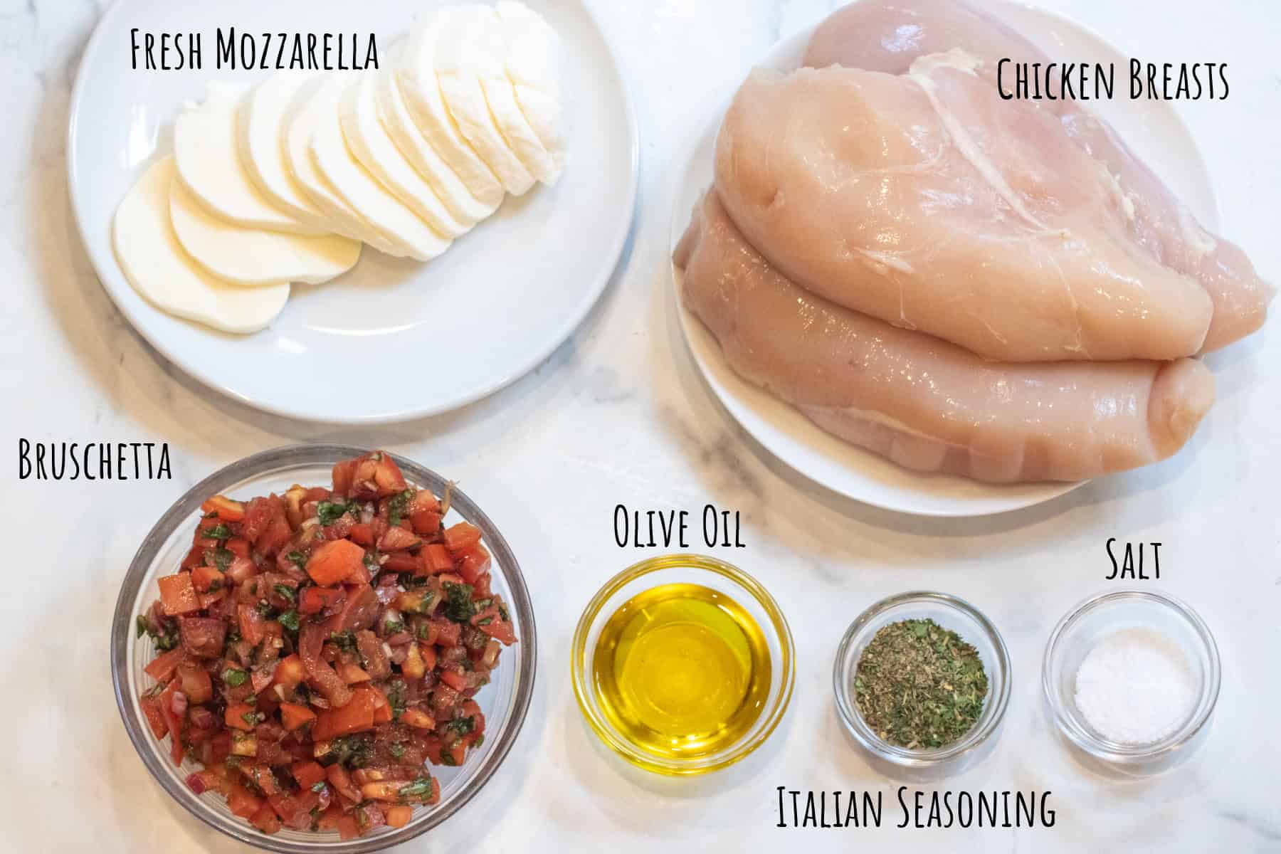 a plate of sliced fresh mozzarella, raw chicken breasts, a bowl of bruschetta, olive oil, Italian seasoning, and salt all labeled.