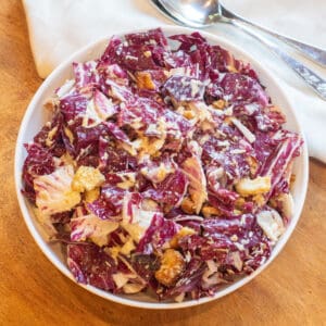 an overhead of a bowl of radicchio salad with dressing and croutons.